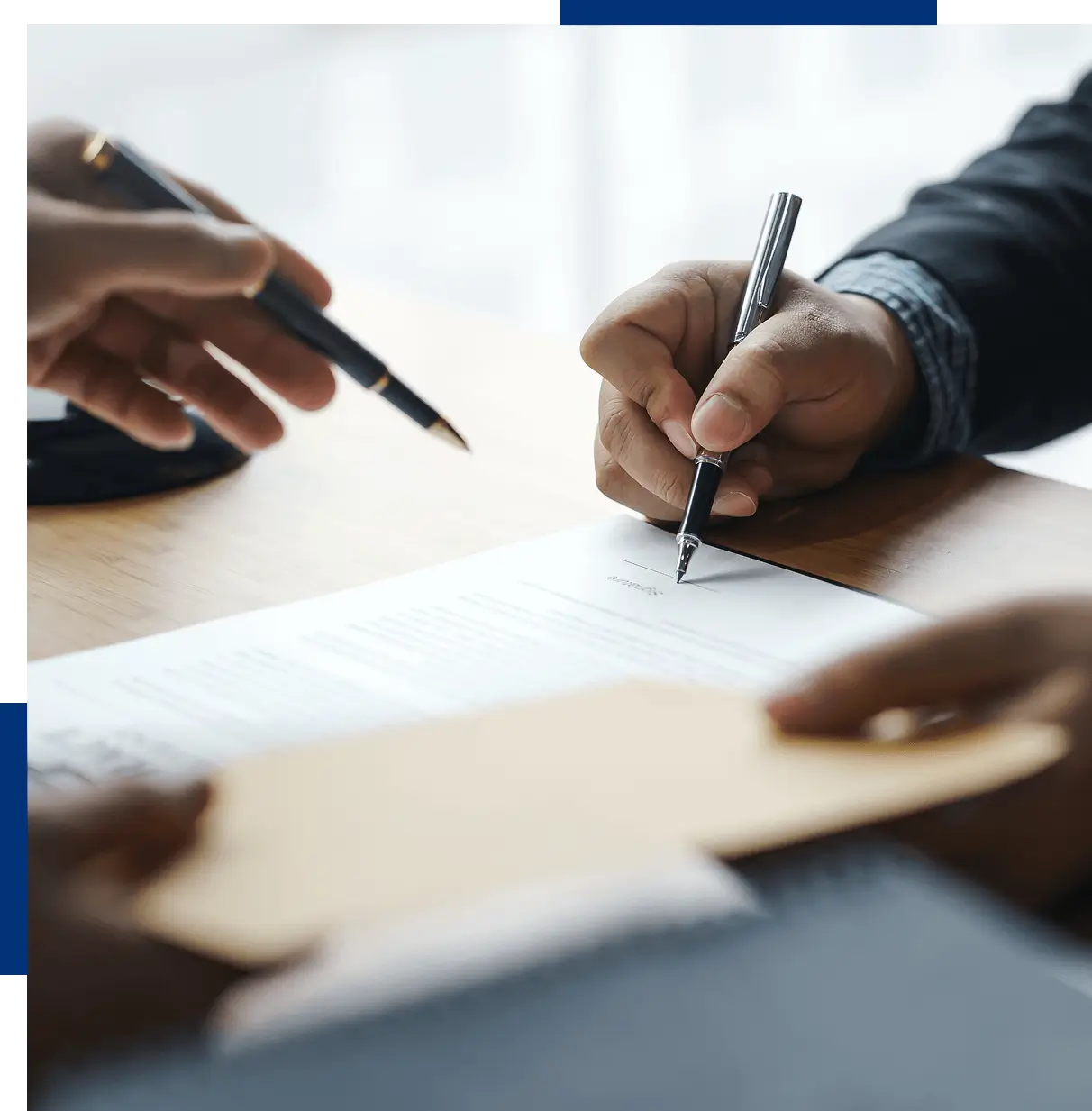 A group of people sitting at a table with pens and paper.